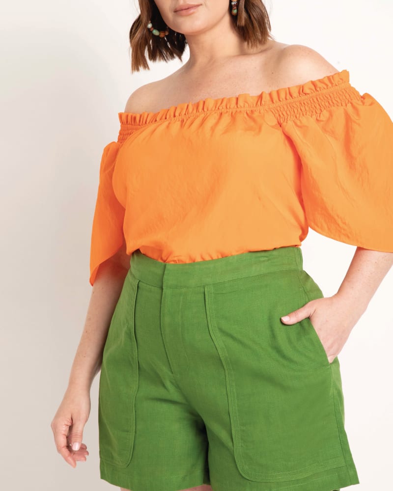 Front of a model wearing a size 14 Alexa Flutter Sleeve Blouse in Exotic Orange by ELOQUII. | dia_product_style_image_id:204087